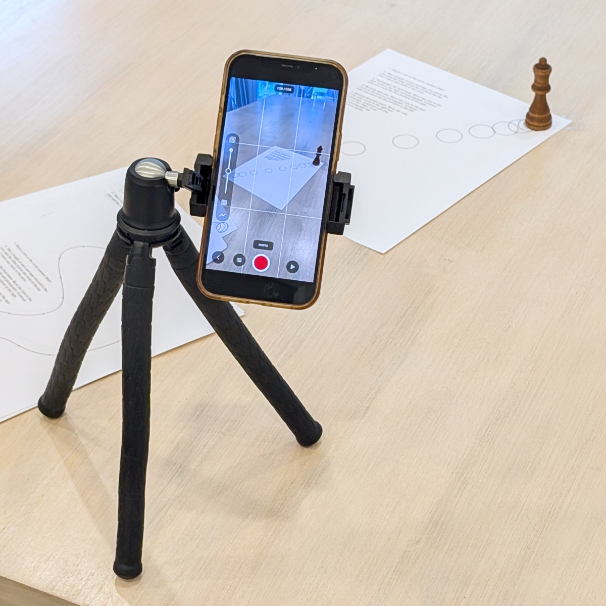 A phone on a small tripod, aimed at an object on the table