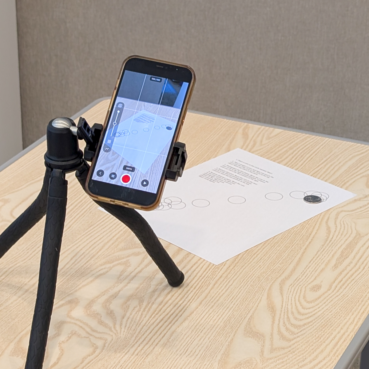 A phone on a tripod filming the printed activity page on a table