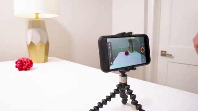 A phone on a small tripod, aimed at an object on the table