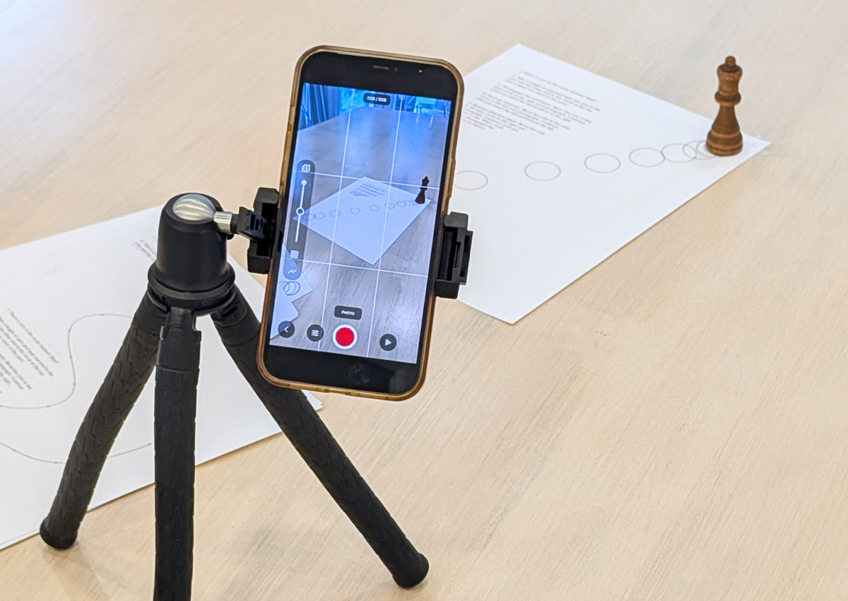 A phone on a small tripod, aimed at an object on the table